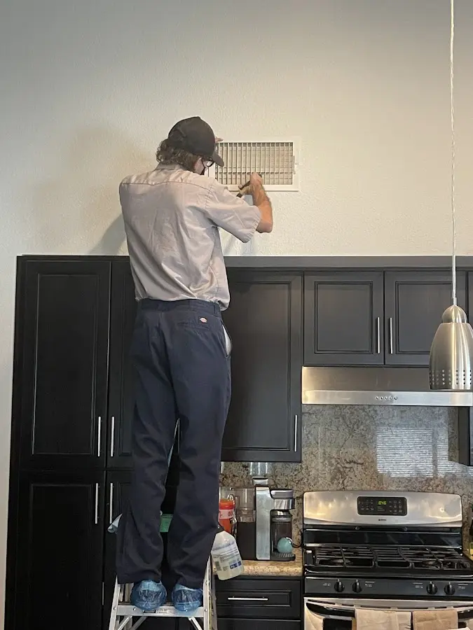 Technician inspecting an air vent during HVAC service in Mountainside